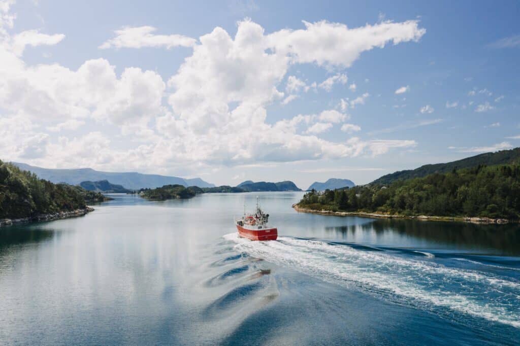 Sustainable romantic getaways. A beautiful shot of a boat on the body of the water surrounded by trees under a clear blue sky with white clouds