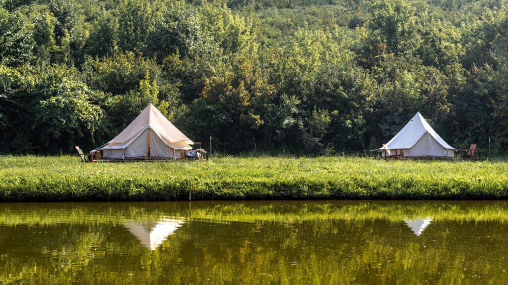 Sustainable romantic getaways. Glamping, few tents, lake on the foreground, geenery around