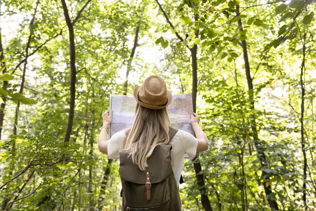 What the importance of sustainable tourism in preserving heritage sites? Woman looking at a map in a forest.